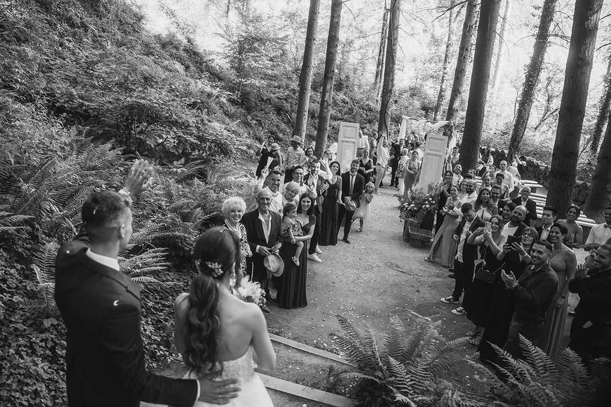 Una novia y un novio caminan hacia el altar en su boda en el bosque.
