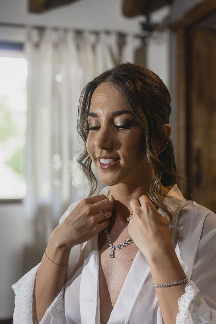 Una mujer con una túnica blanca se pone un collar.