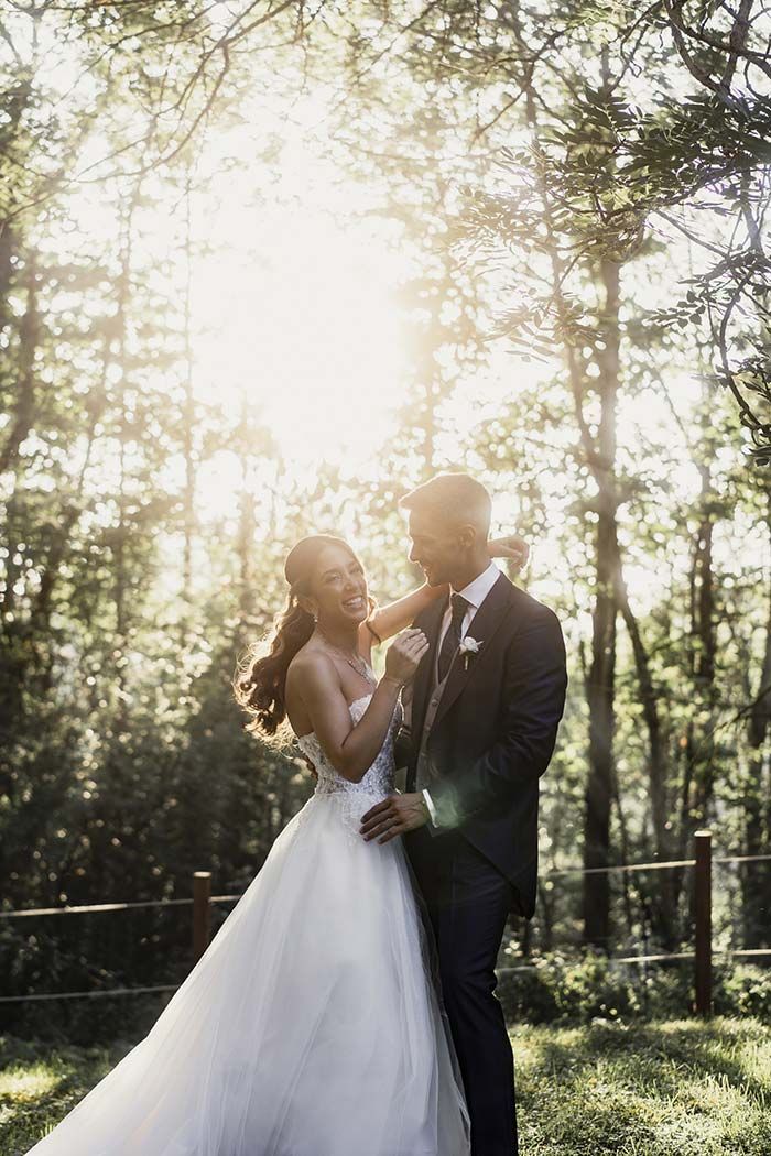 Una novia y un novio posan para una fotografía en el bosque.