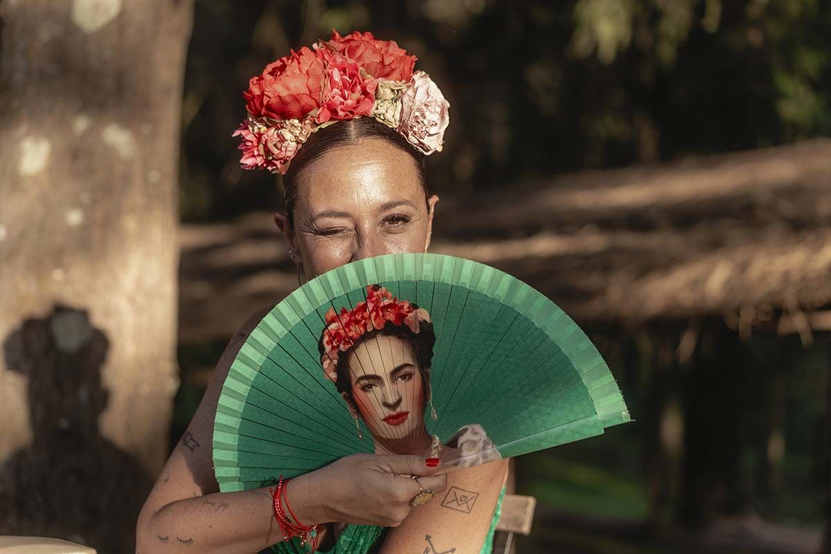 Una mujer sostiene un abanico verde con una imagen de Frida Kahlo.