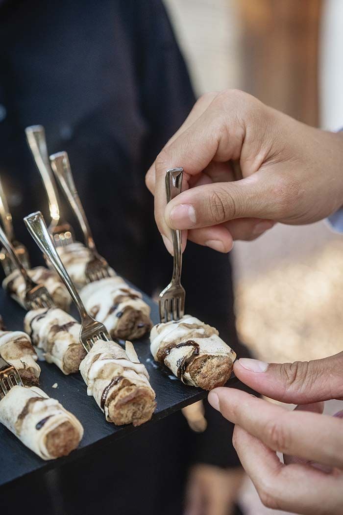 Una persona sostiene un tenedor sobre una bandeja de comida.