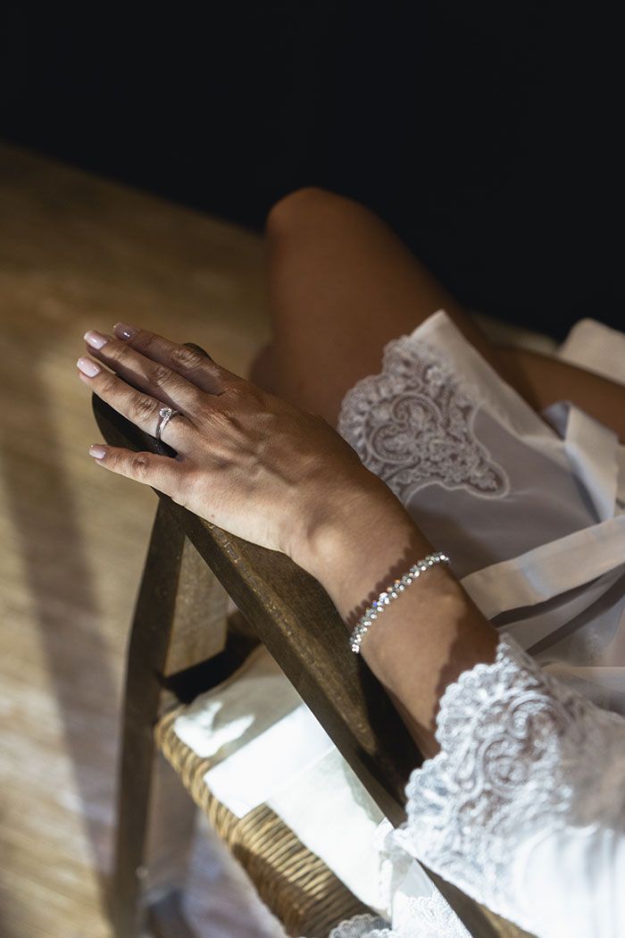 Una mujer que lleva una pulsera y un anillo está sentada en una silla.