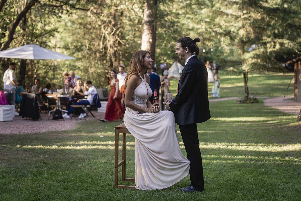 Una novia y un novio están sentados en un taburete de madera en un parque.