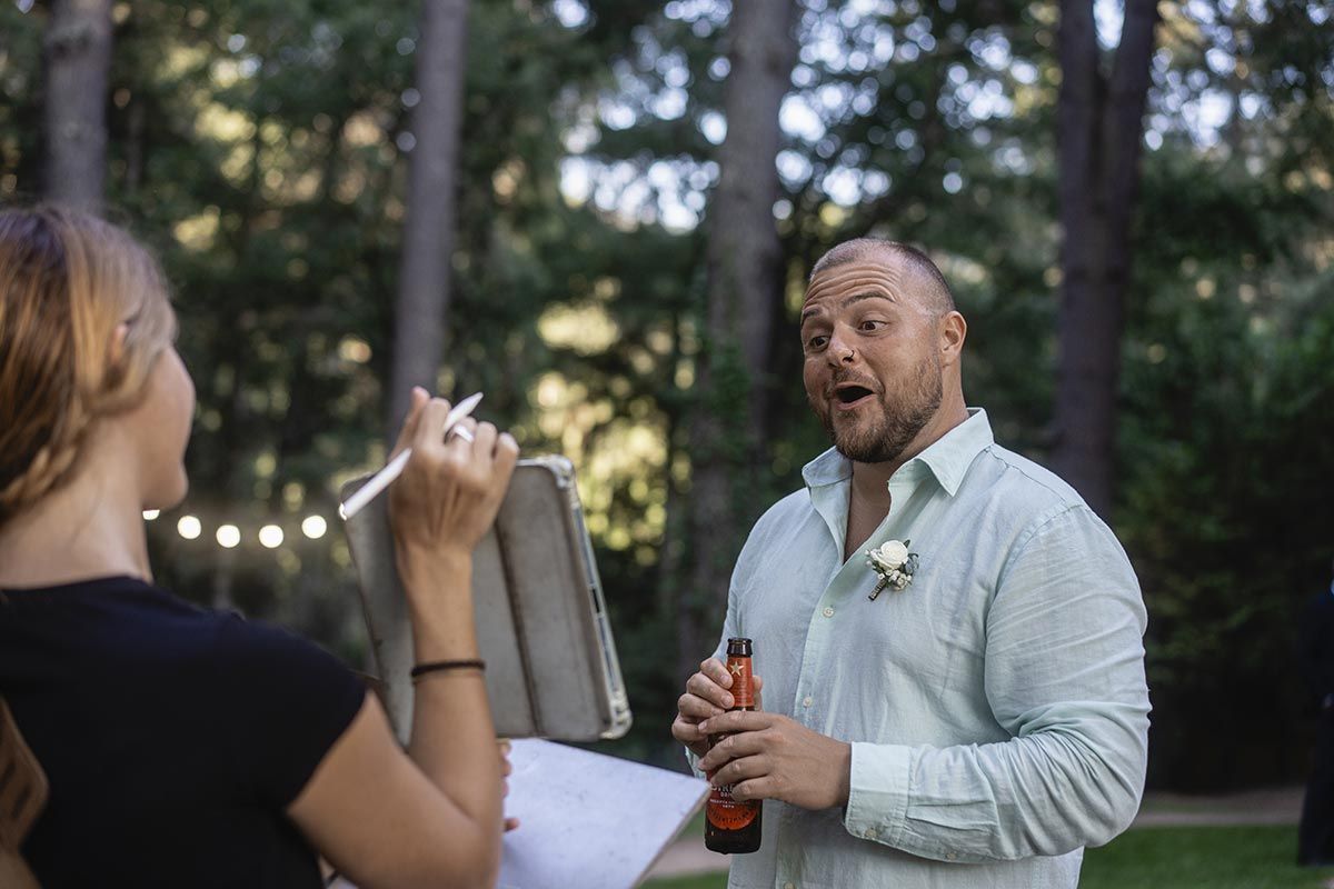 Un hombre sostiene una botella de cerveza y habla con una mujer.