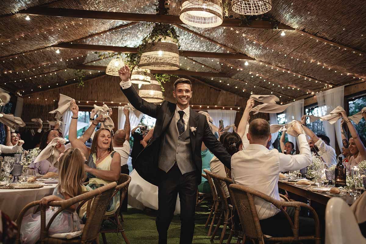 Un hombre con traje camina entre una multitud de personas en una recepción de boda.