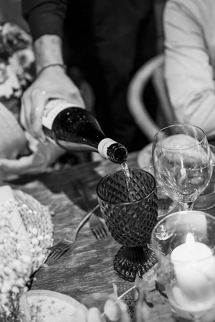 Una persona está vertiendo vino en una copa sobre una mesa.