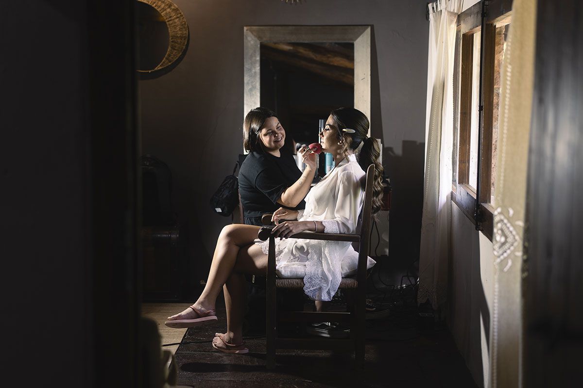 Una mujer está sentada en una silla mientras se peina frente a un espejo.