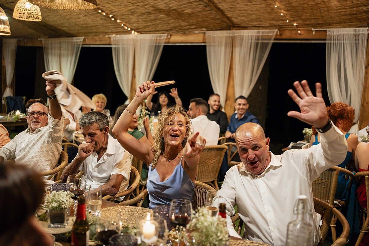 Un grupo de personas está sentada en una mesa con las manos en el aire.