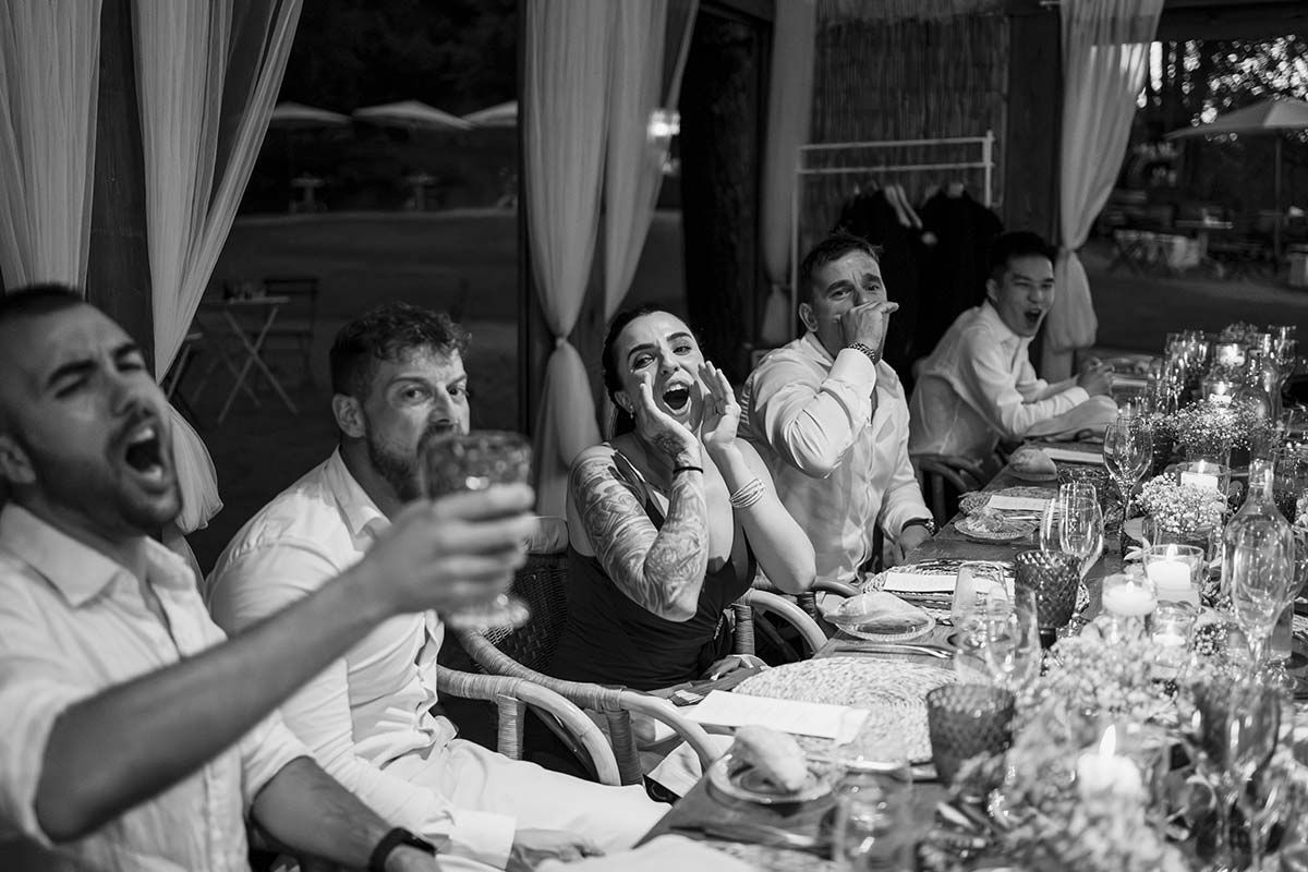 Un grupo de personas está sentado en una mesa larga con copas de vino.