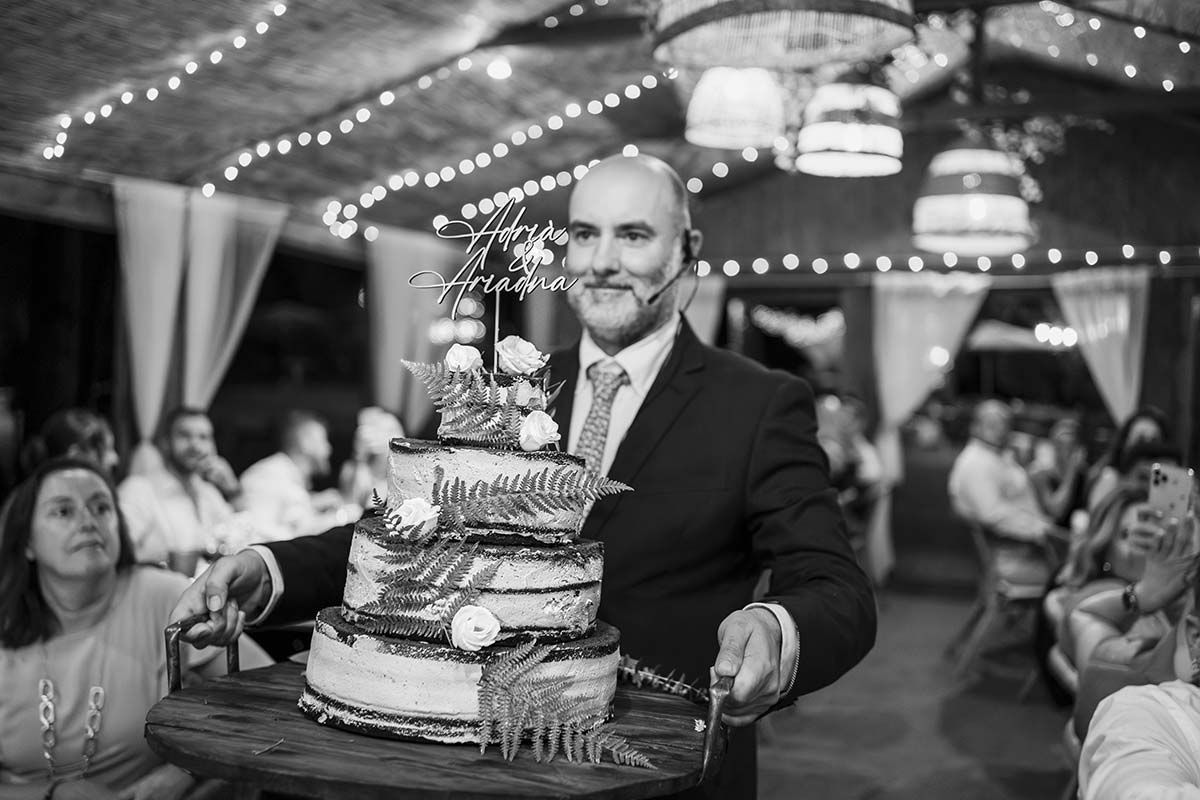 Un hombre está cortando un pastel de bodas en una foto en blanco y negro.