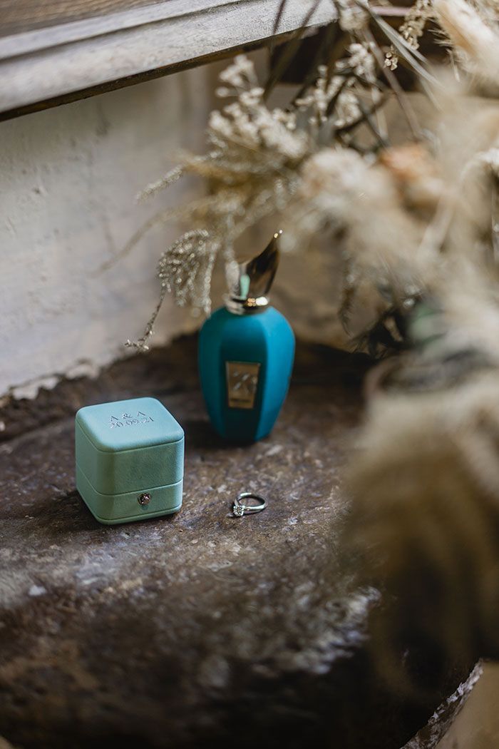 Una botella de perfume está sobre una roca al lado de una pastilla de jabón.