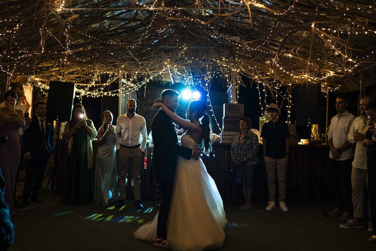 Una novia y un novio están bailando en la recepción de su boda bajo un dosel de luces.