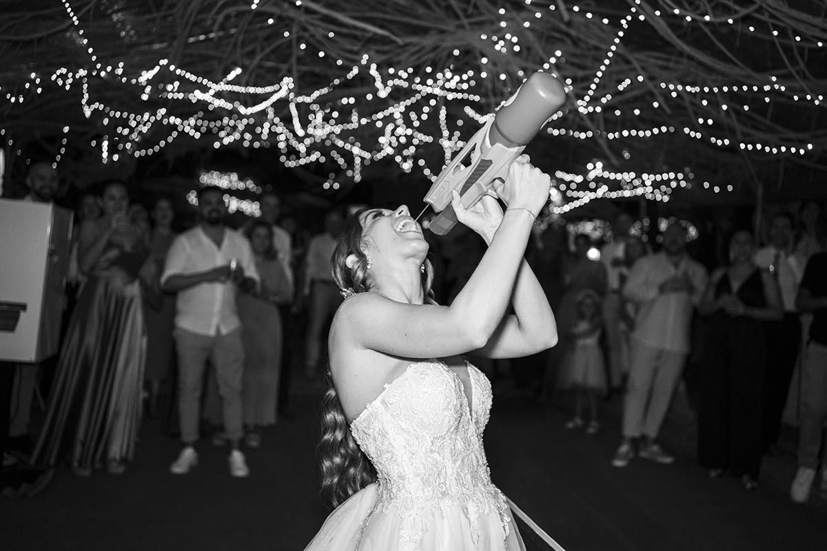 Una mujer con un vestido de novia sostiene una botella en su mano.