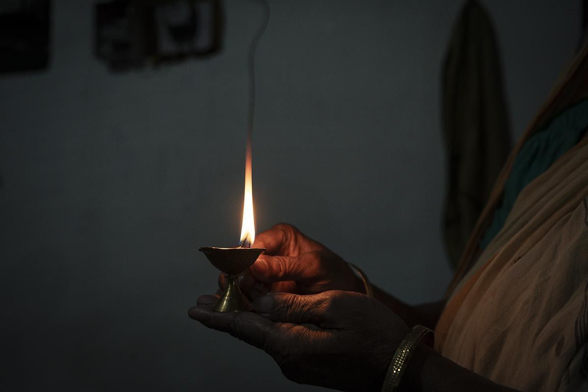 Una persona sostiene una vela encendida en su mano.