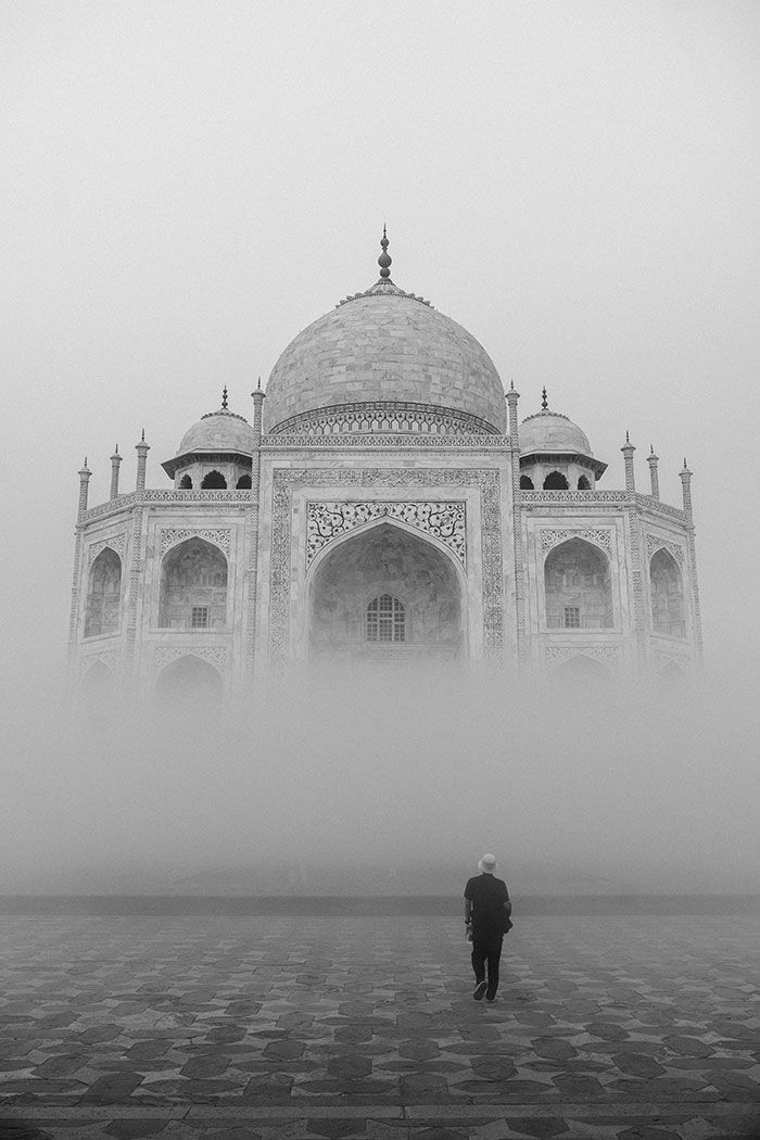 Un hombre camina frente a una mezquita en la niebla.