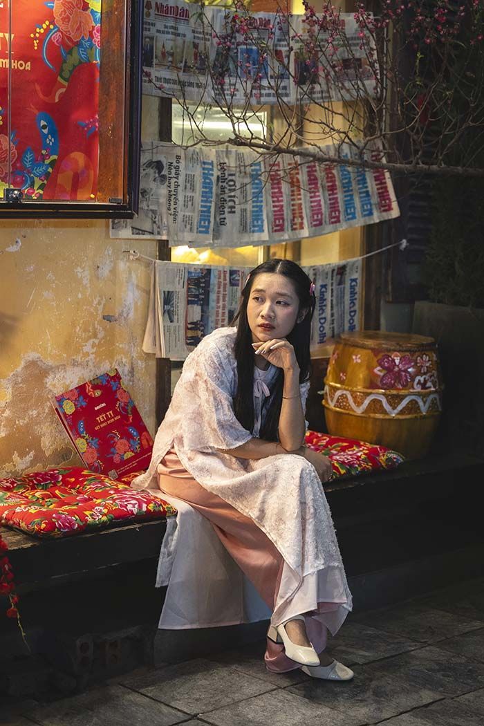 Una mujer con un vestido blanco está sentada en un banco.