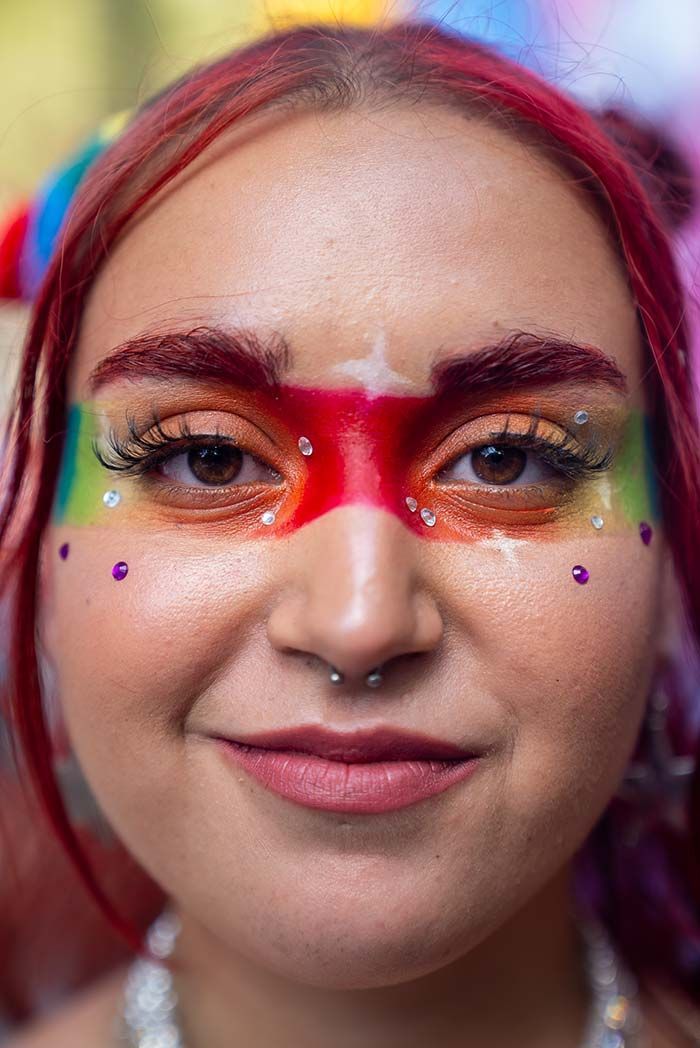 Un primer plano de una mujer con maquillaje de arcoíris en su cara.