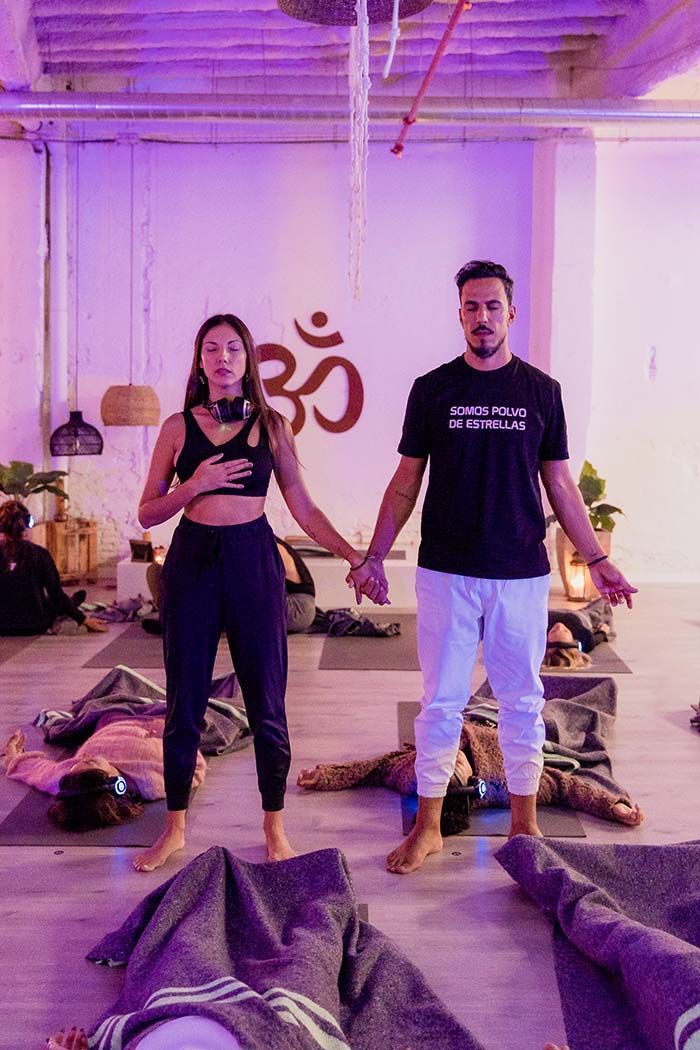 Un hombre y una mujer se toman de la mano en un estudio de yoga.