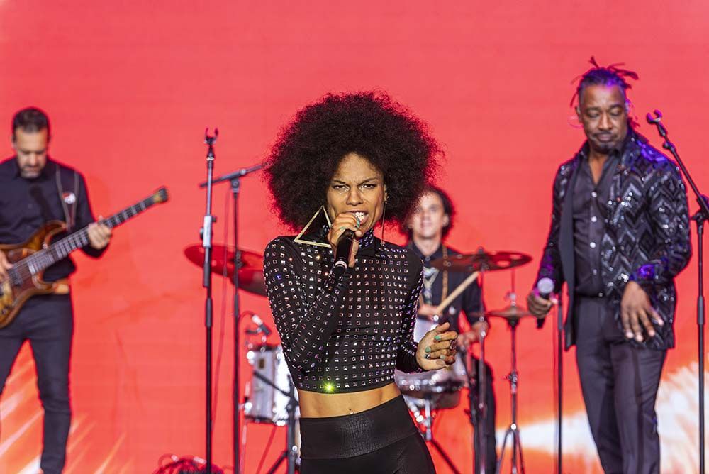 Una mujer está cantando en un micrófono en un escenario con una banda.