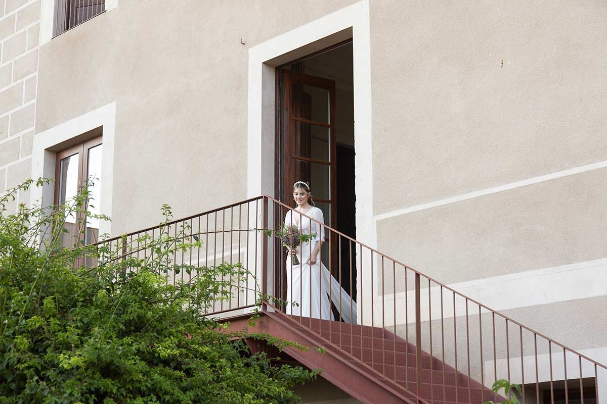 Una mujer con un vestido de novia está parada en un tramo de escaleras.