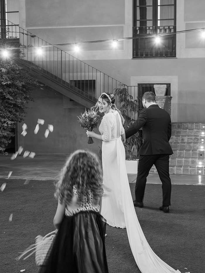 Una novia y un novio caminan por el pasillo con una niña de las flores en una foto en blanco y negro.