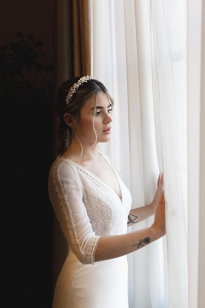 Una mujer con un vestido de novia está mirando por una ventana.