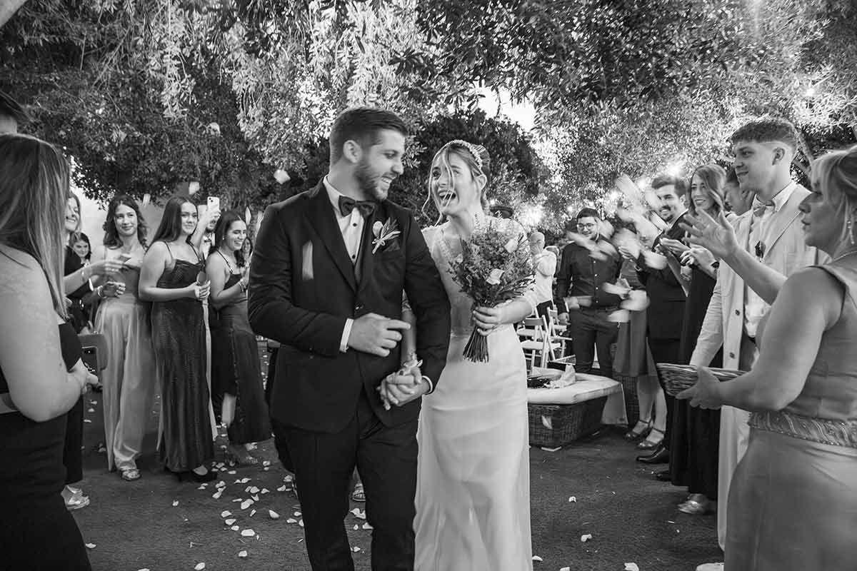 Una fotografía en blanco y negro de una novia y un novio caminando por el pasillo en su boda.