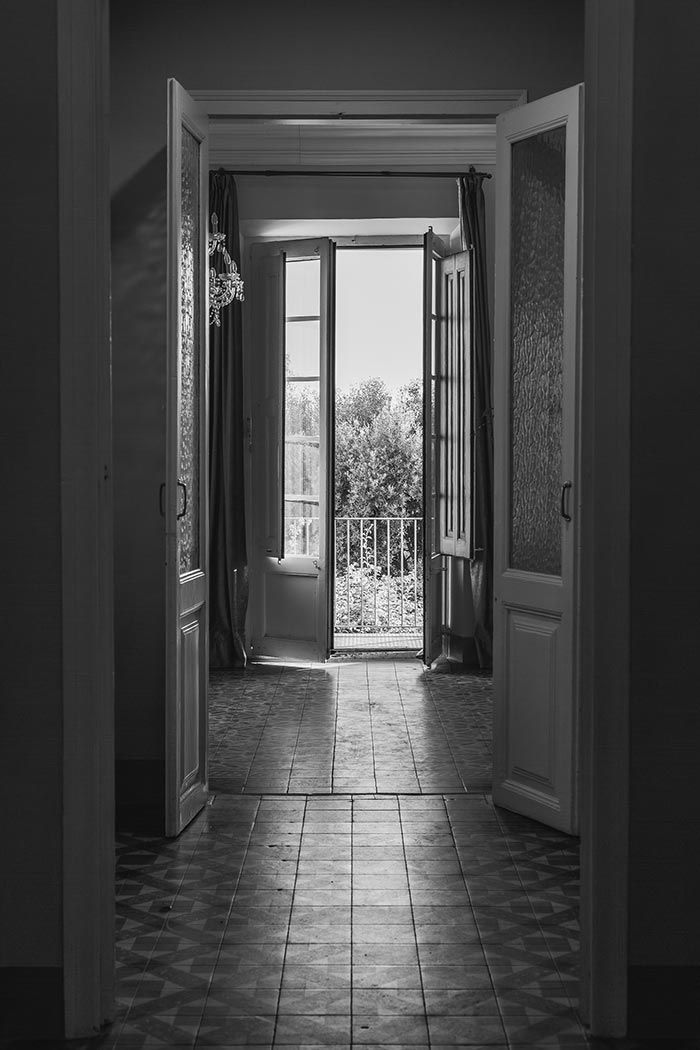 Una fotografía en blanco y negro de una puerta abierta que conduce a un balcón.