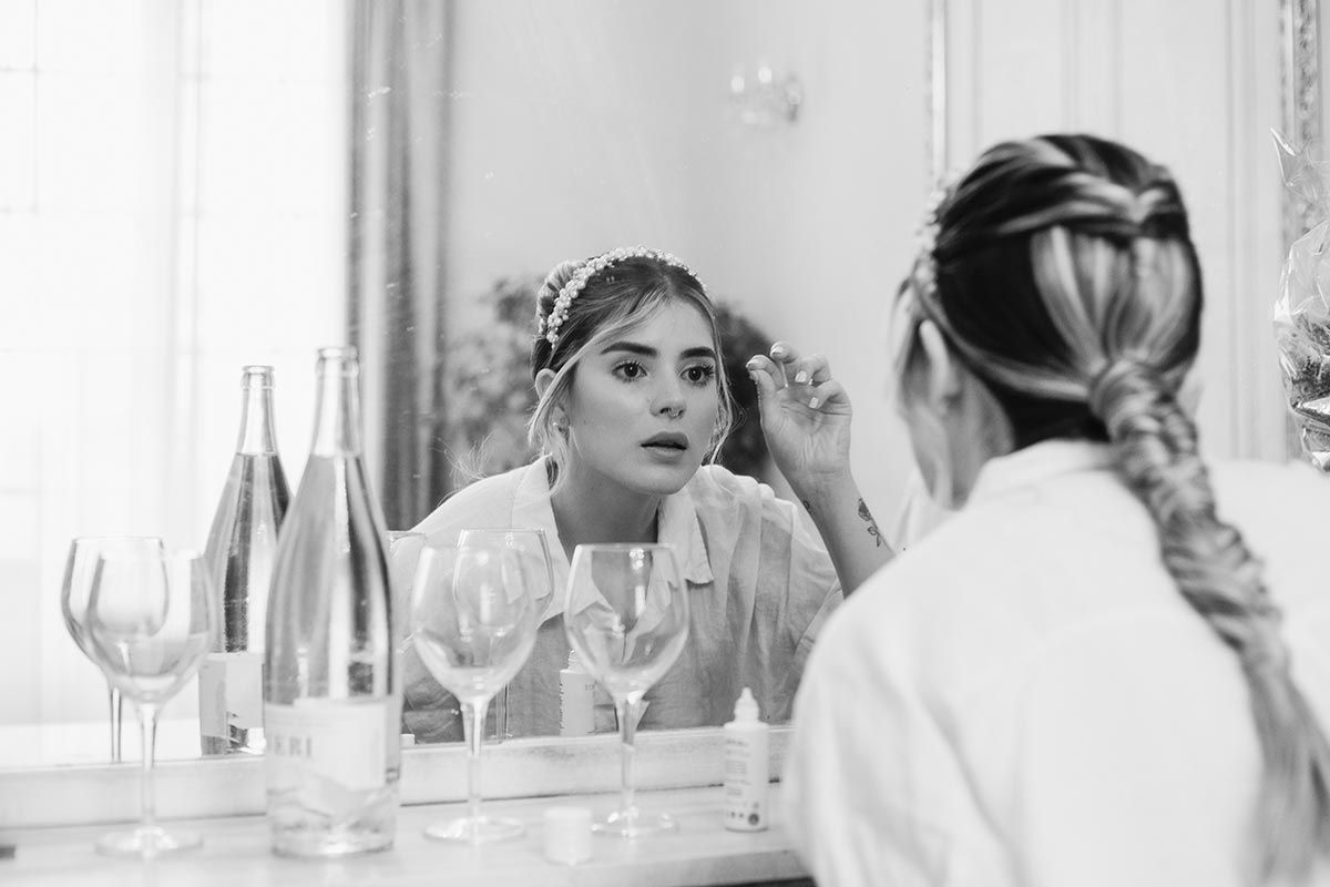 Una mujer se está maquillando frente a un espejo.