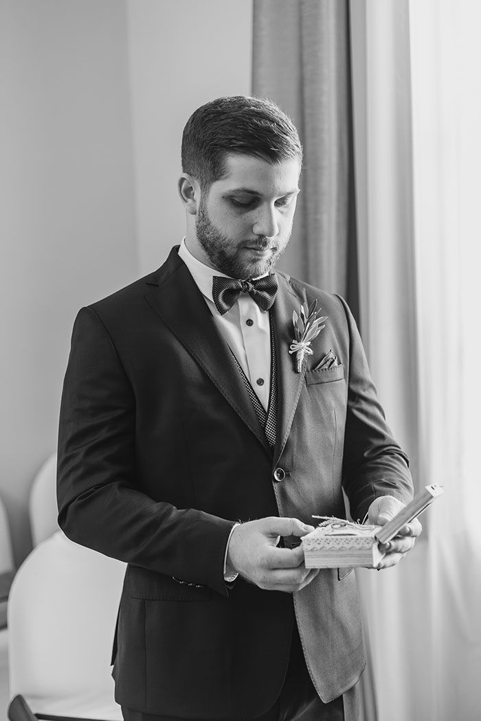 Una fotografía en blanco y negro de un hombre con esmoquin sosteniendo una caja.