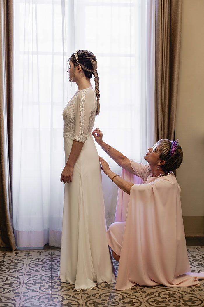 Una mujer está ayudando a una novia a prepararse para su boda.