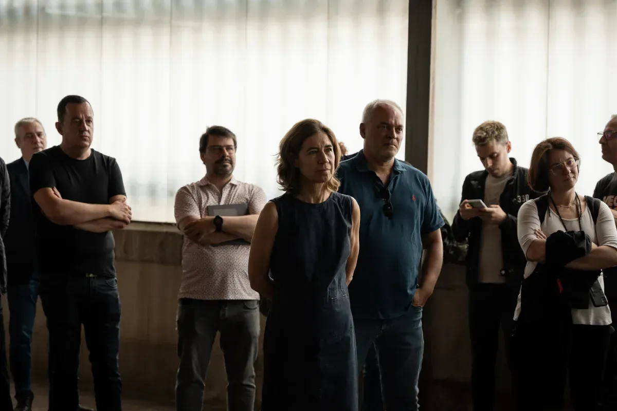 Un grupo de personas están de pie en una habitación con los brazos cruzados.