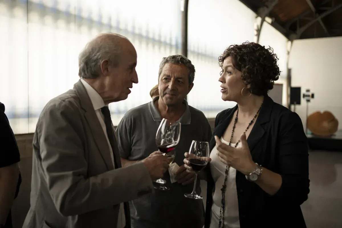 Un grupo de personas está hablando y bebiendo vino.
