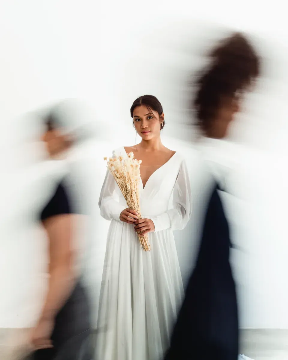 Una mujer con un vestido blanco sostiene un ramo de flores secas.