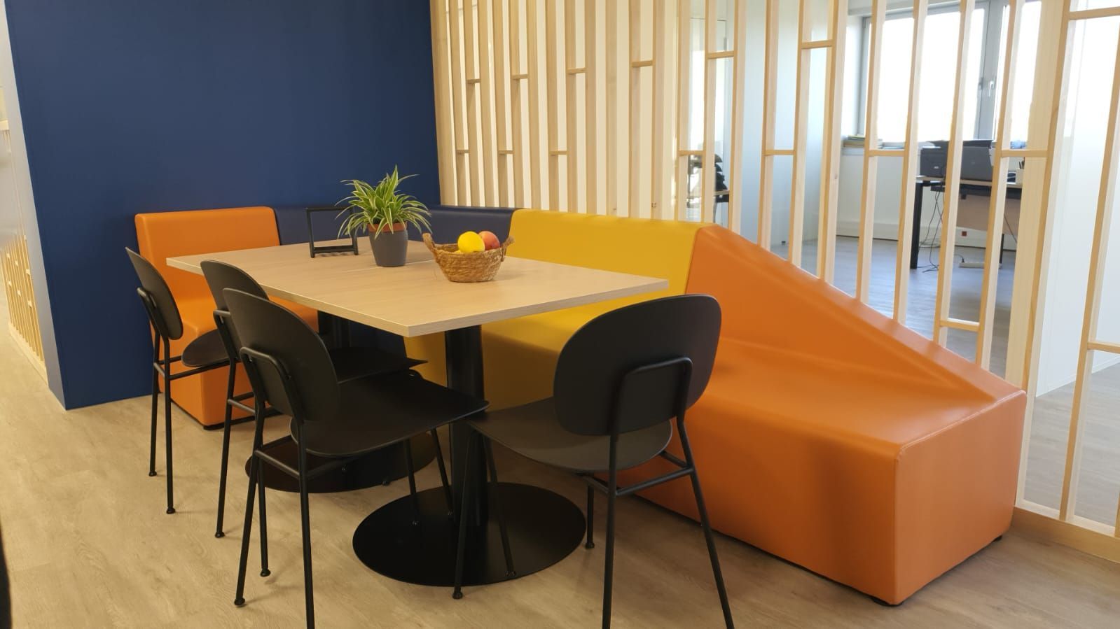 Table avec chaises noires et canapé coloré