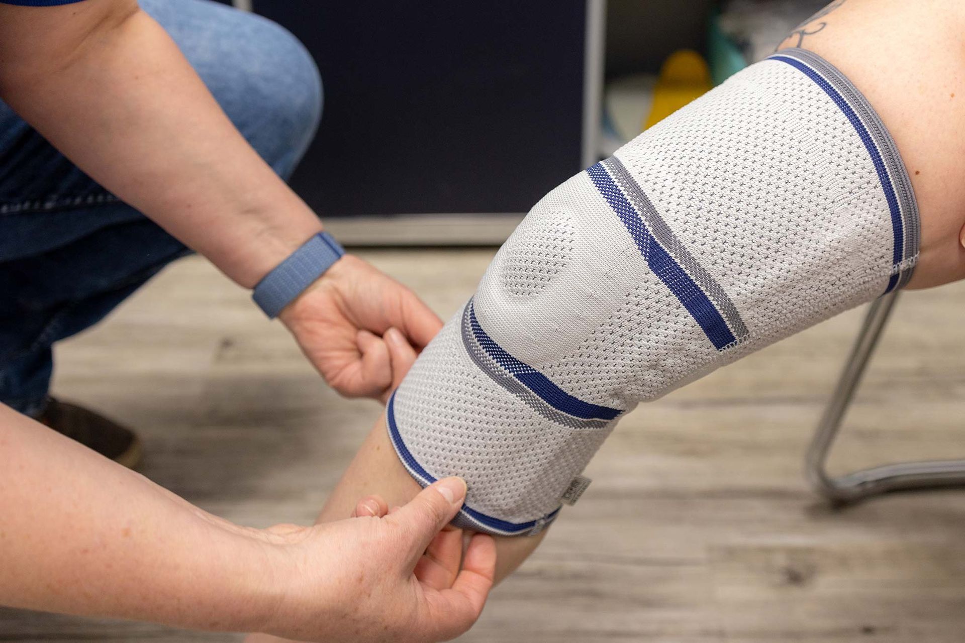 Eine Person legt einer anderen Person eine Knieorthese an das Bein.