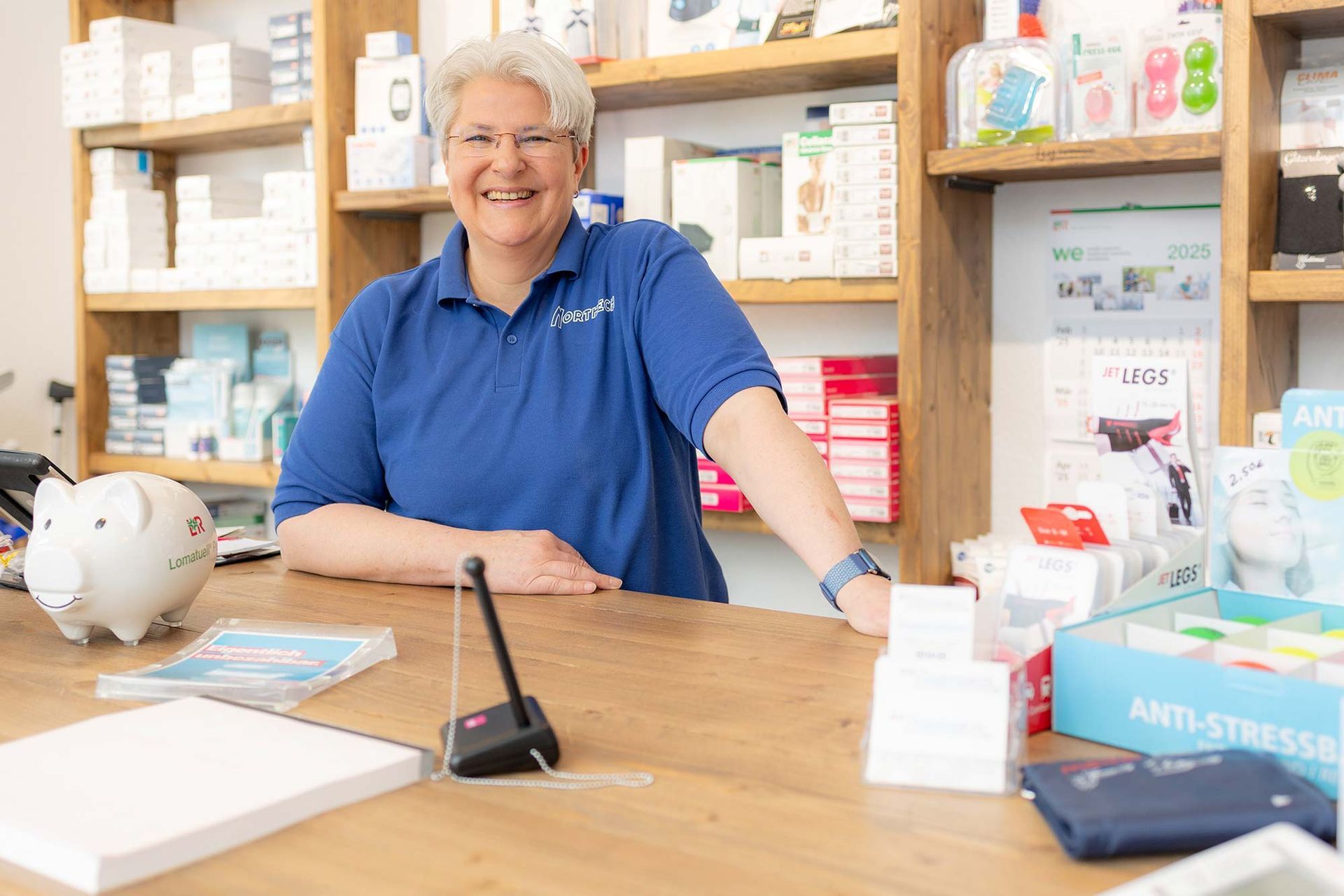 Eine Frau sitzt an einem Tresen in einer Apotheke.