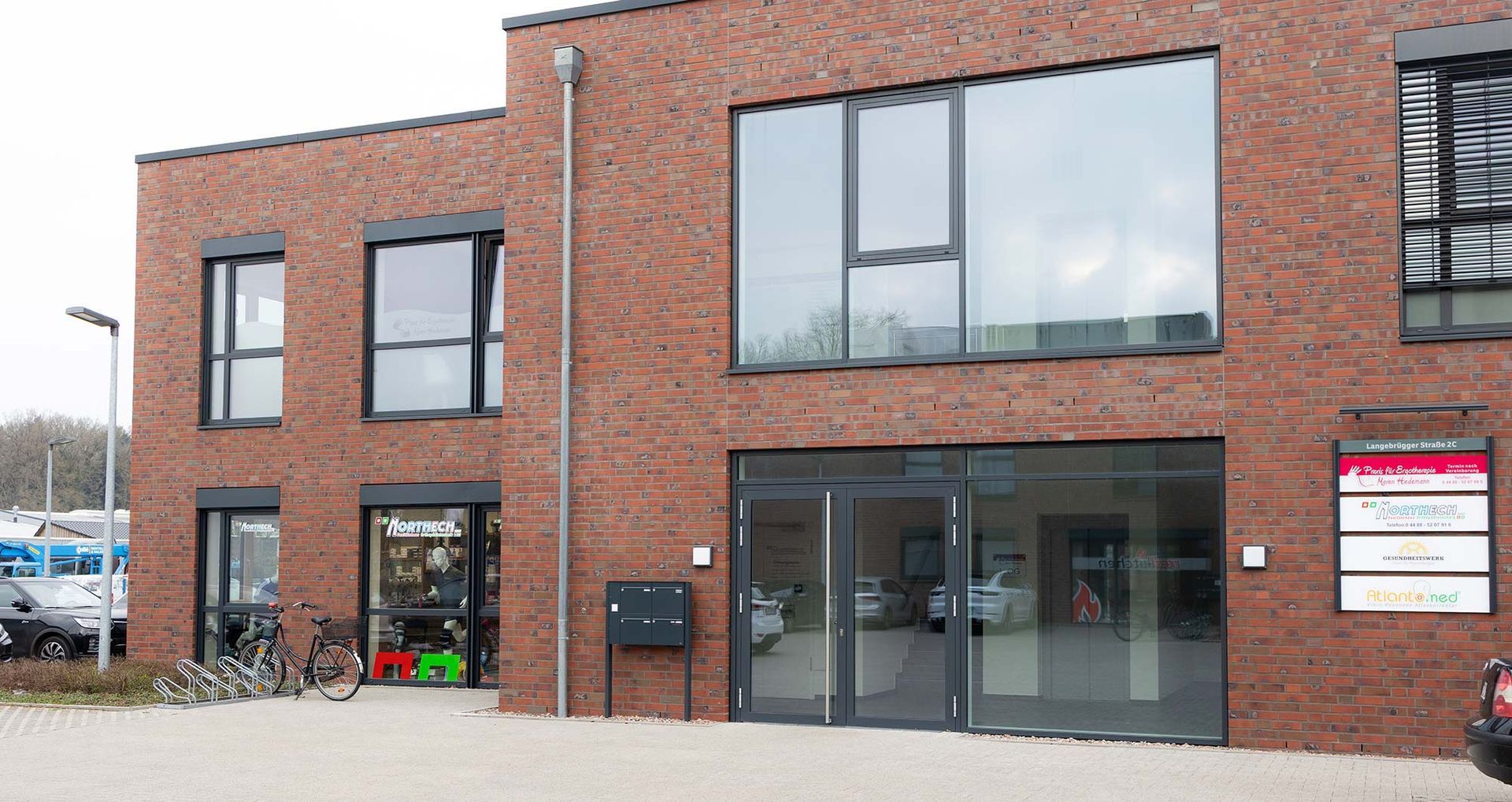 Ein Backsteingebäude mit vielen Fenstern und einem davor geparkten Auto.