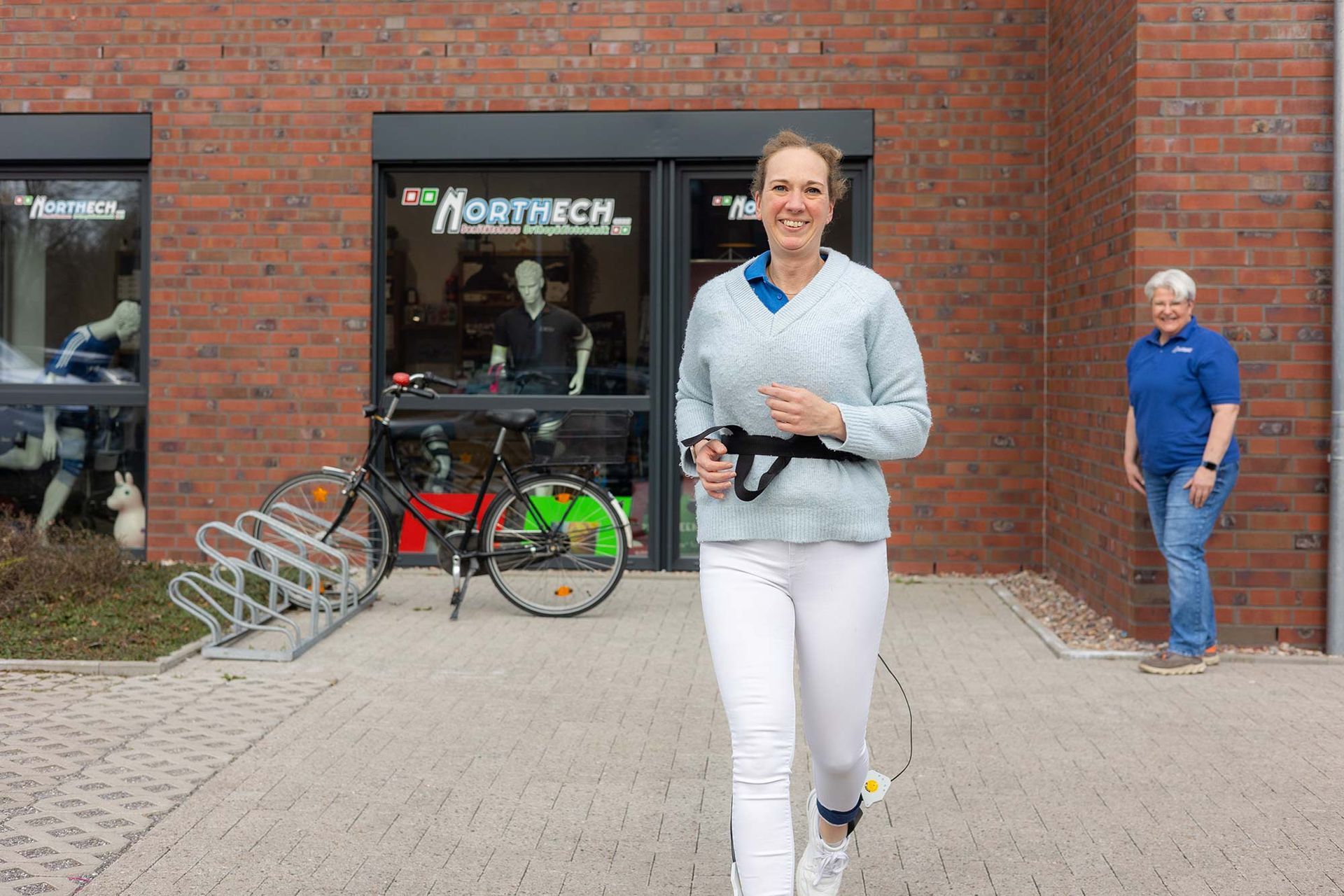 Eine Frau rennt vor einem Backsteingebäude.