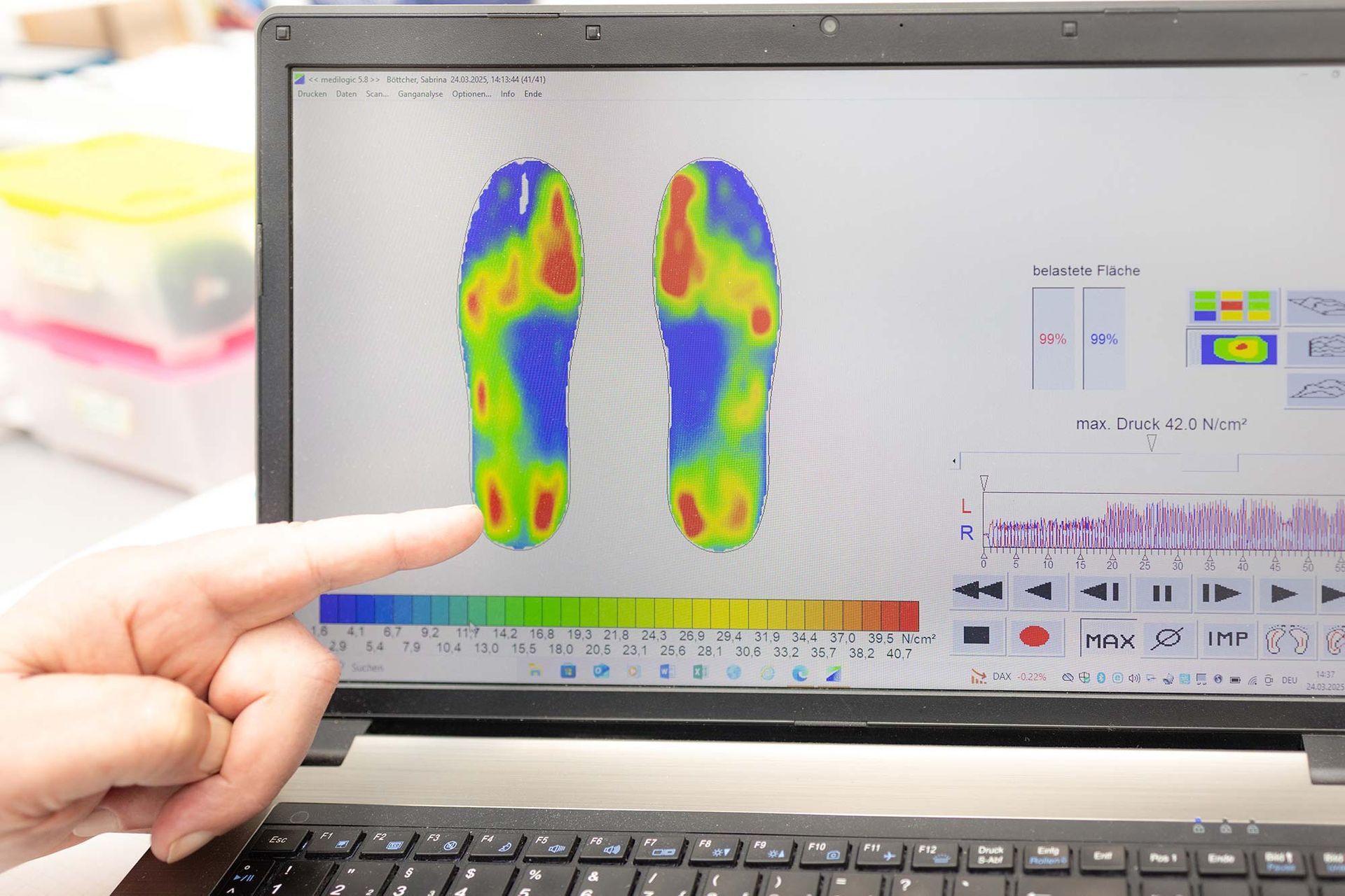 Eine Person zeigt auf einen Laptop-Bildschirm mit Fußabdrücken darauf.