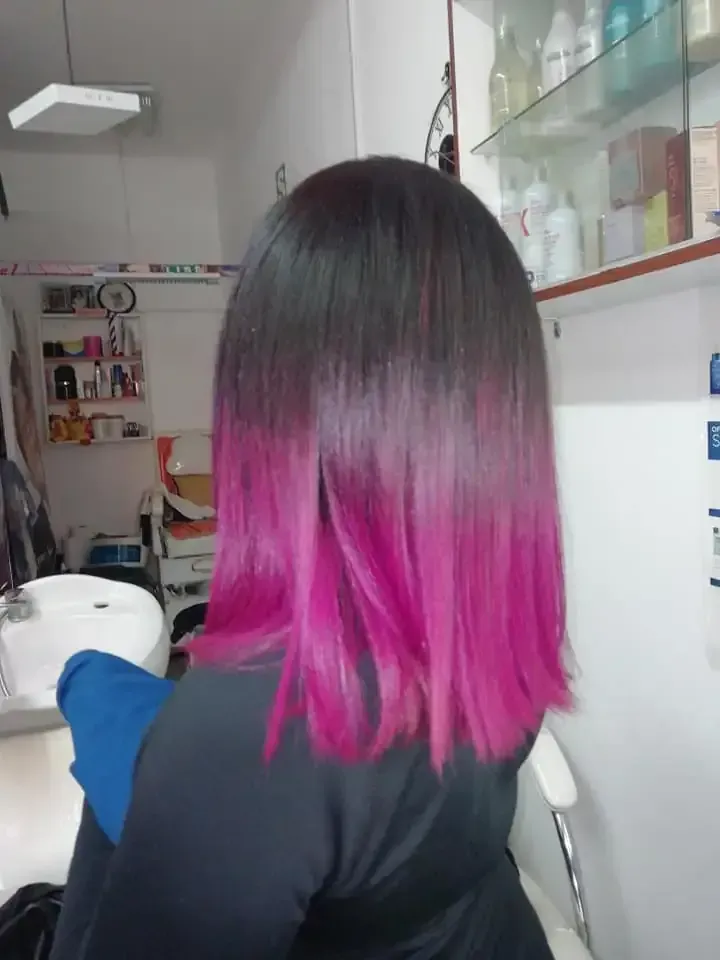 Cabello ombré de color oscuro a rosado en una persona en un salón, de espaldas.