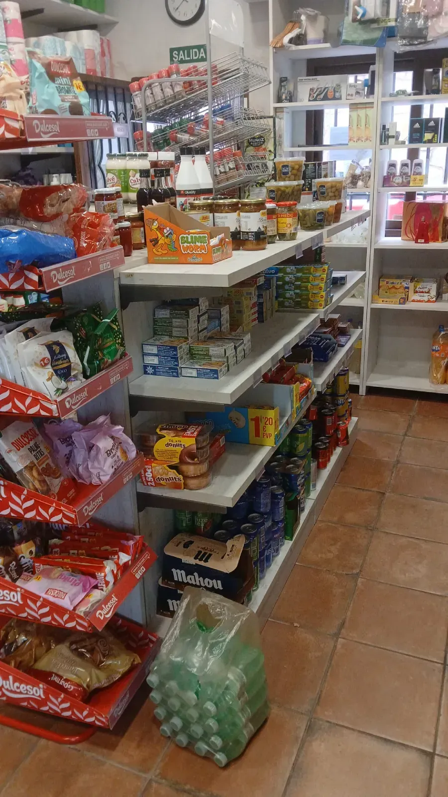 Estantes llenos de alimentos envasados ​​dentro de una tienda, una bolsa de botellas de agua en el suelo.