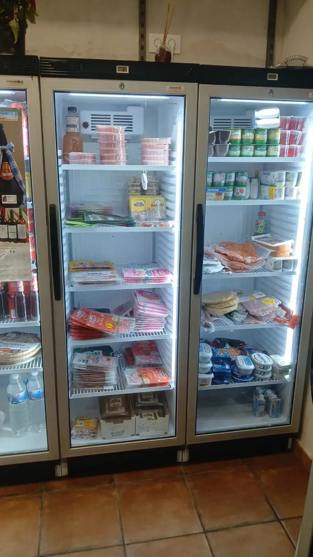 Tres vitrinas refrigeradas llenas de alimentos envasados.