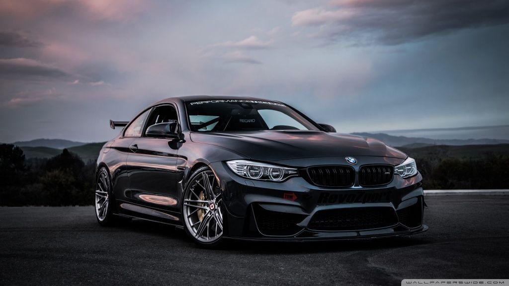 Un BMW M4 negro está estacionado al costado de la carretera.