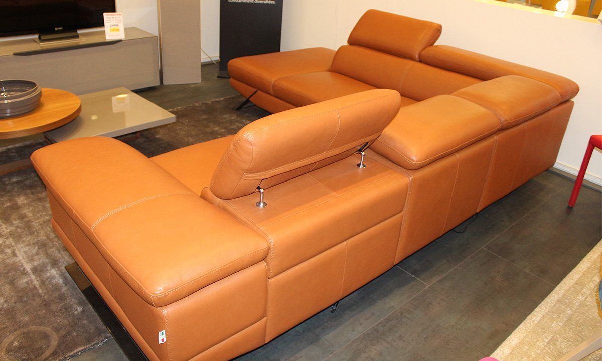 Salon aménagé avec canapé d'angle en cuir marron vue sur le dosser avec les tétières relevées