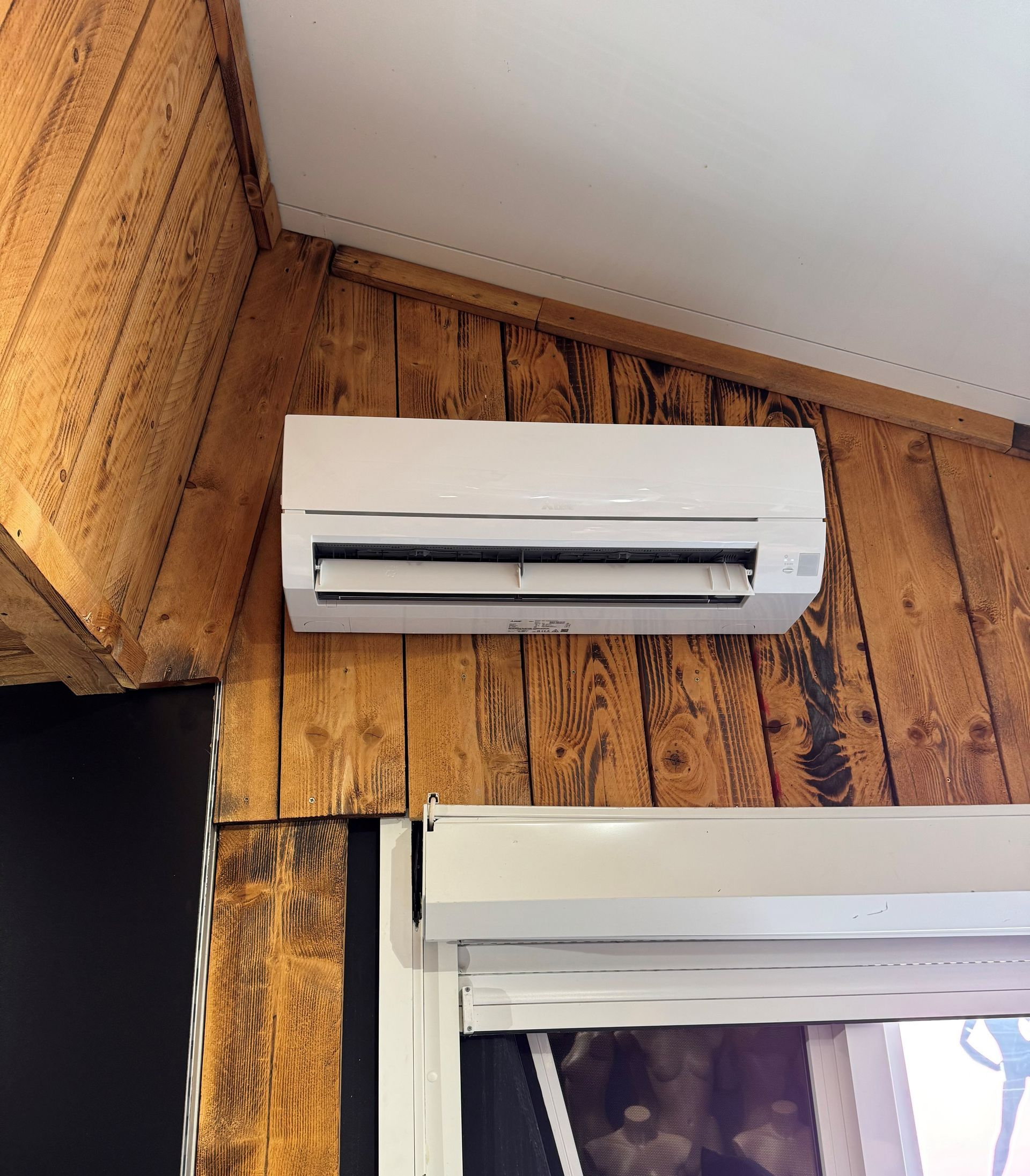 Un climatiseur blanc sur un mur en bois.