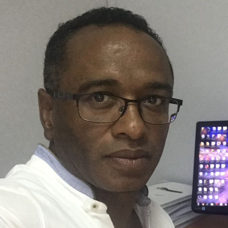 Um homem de óculos e jaleco branco olha para a câmera