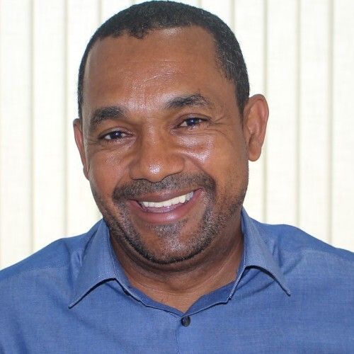 Um homem de camisa azul está sorrindo para a câmera.