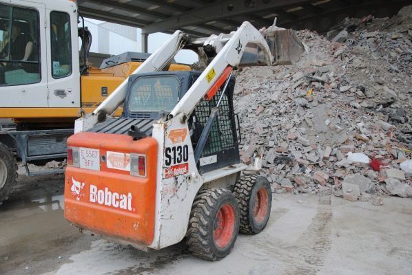 Una minicargadora Bobcat está estacionada frente a una pila de escombros