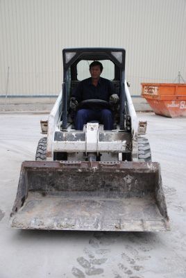 Un hombre conduce una excavadora en un estacionamiento.